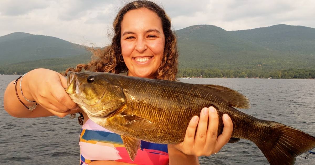 woman holds up fish she caught in lake george