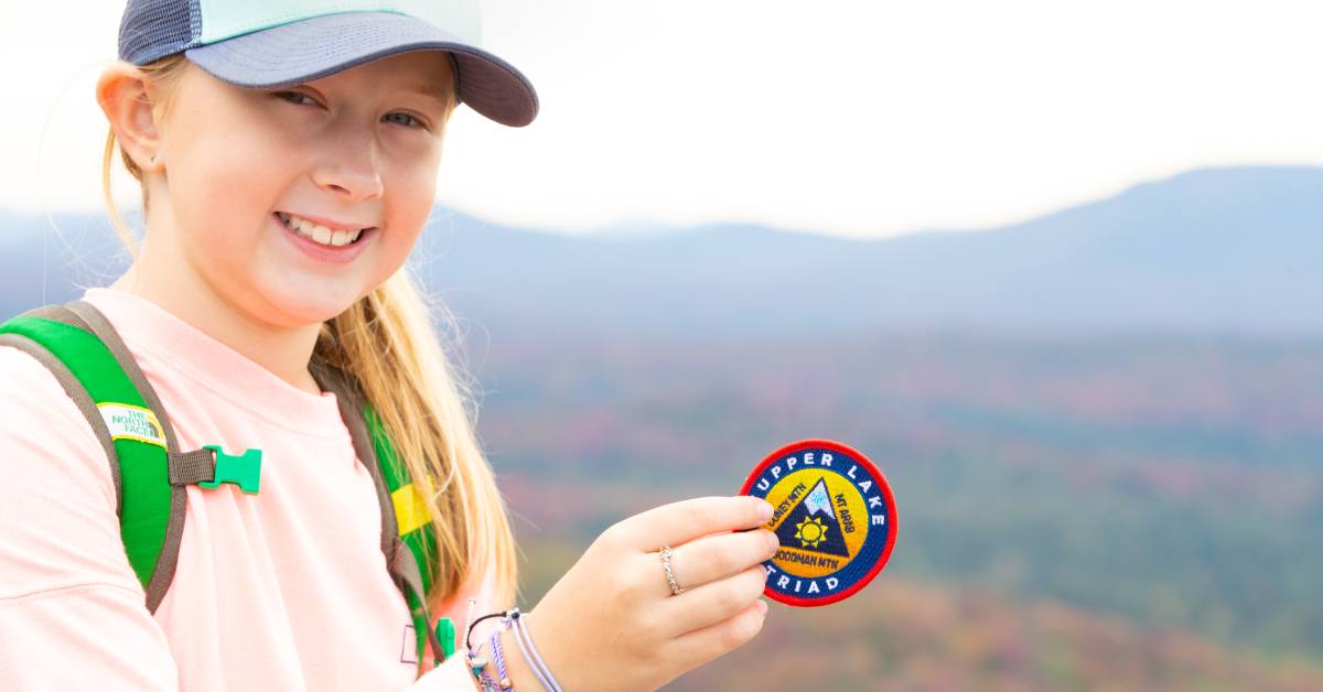 girl holds up tupper lake triad patch