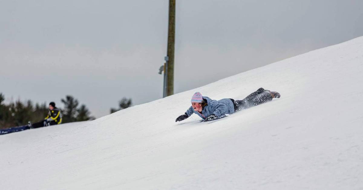 girl snow tubes on her stomach