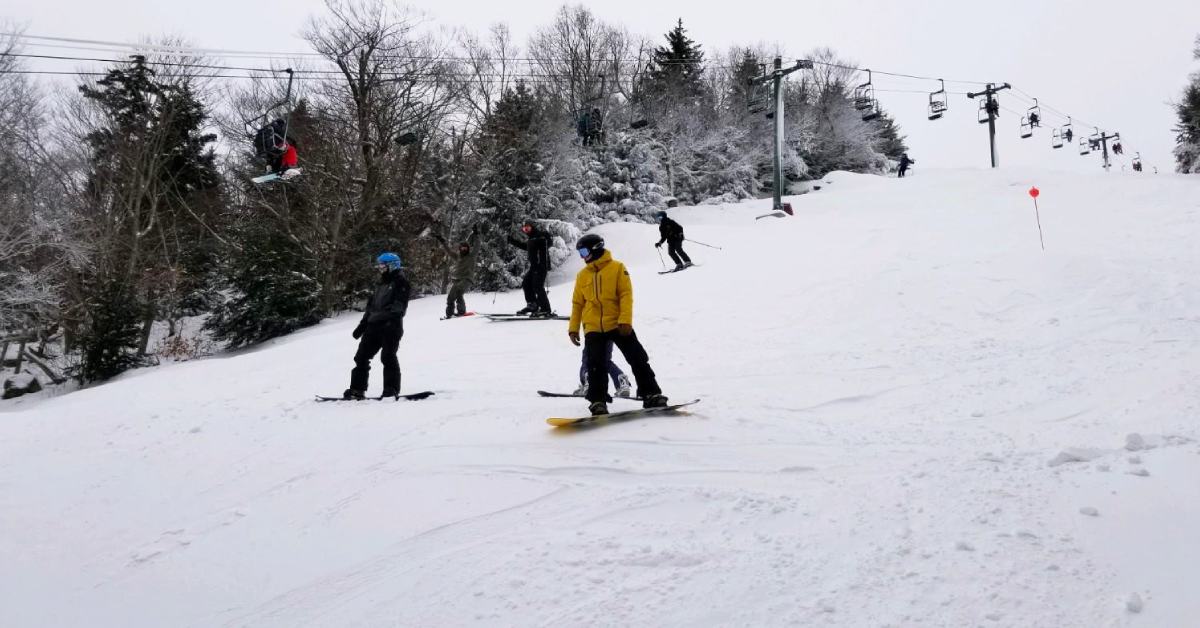 people skiing down a mountain under a chairlift