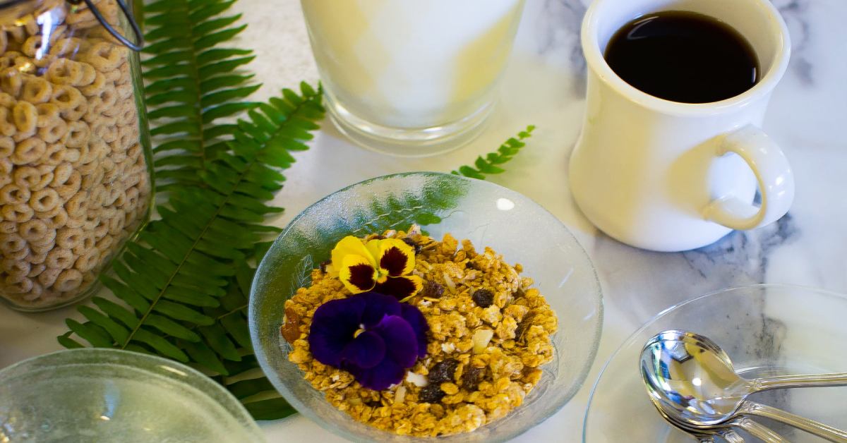 granola with flower petals next to a mug of coffee