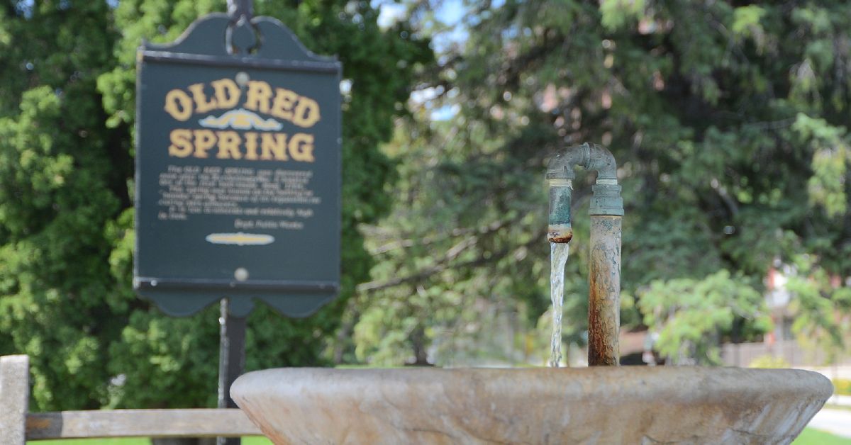 water coming out of old red spring, with its sign in the background