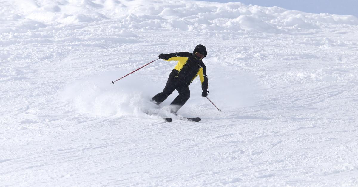 a downhill skier in a yellow and black jacket