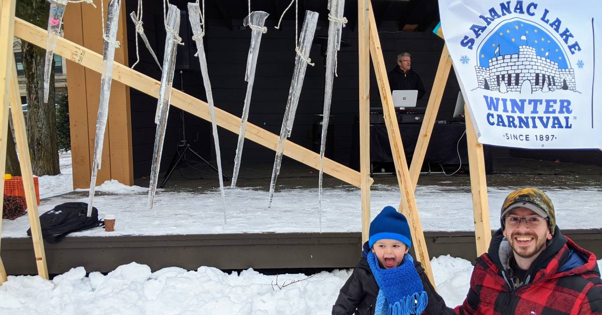 little boy with dad in front of icicle contest at saranac lake winter carnival