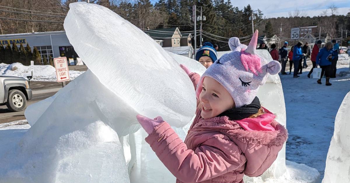 little girl places with ice sculpture of car