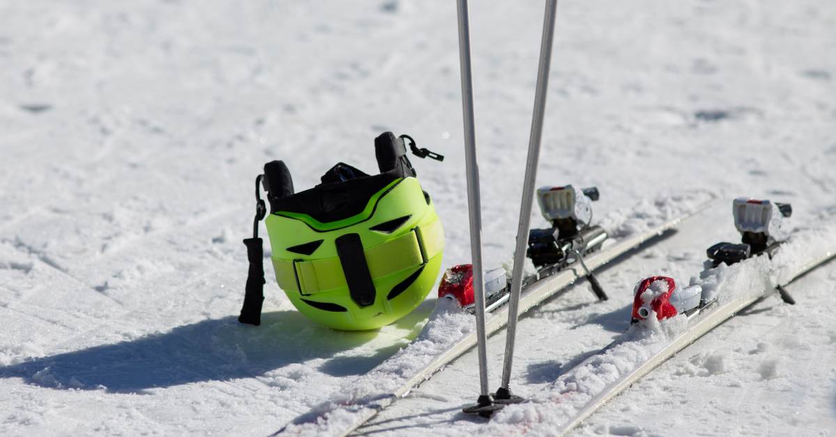 green ski helmet next to skis and poles