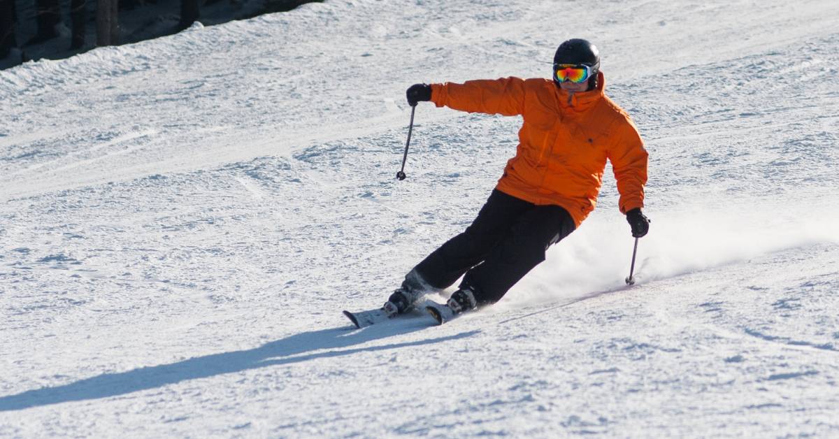 a downhill skier in an orange coat