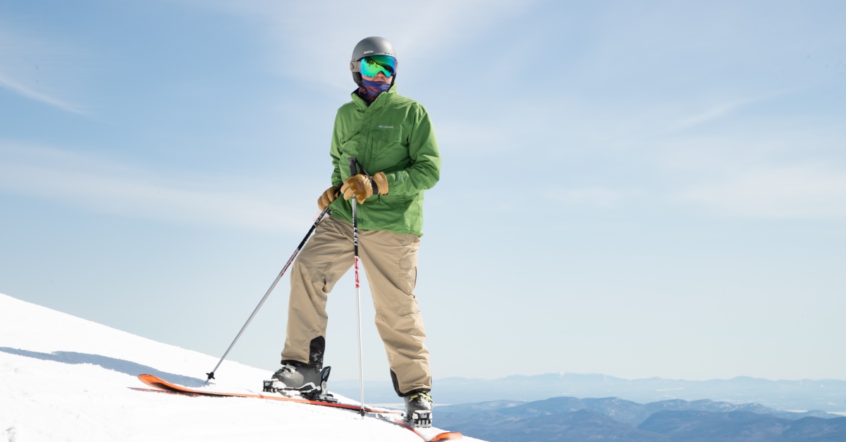 a skier in tan pants and a green coat