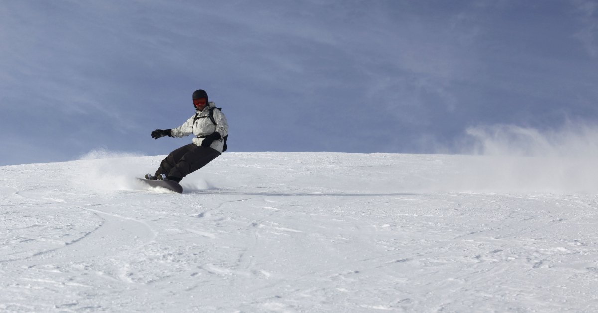 a snowboarding in a white coat and black pants