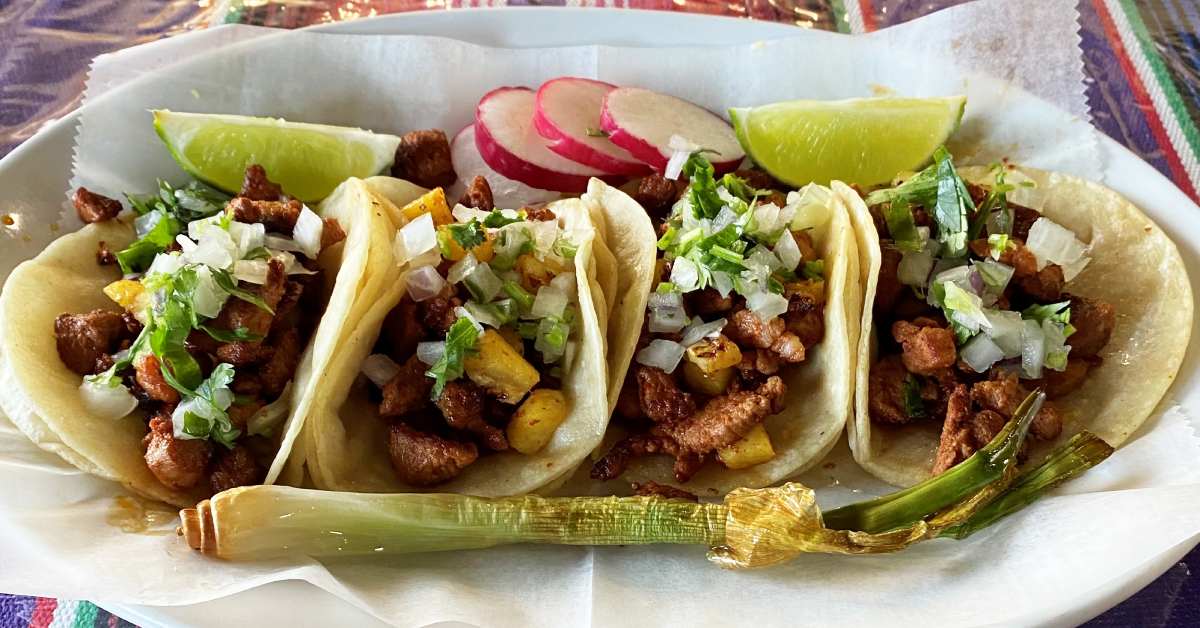 four tacos, radish slices, and lime slices