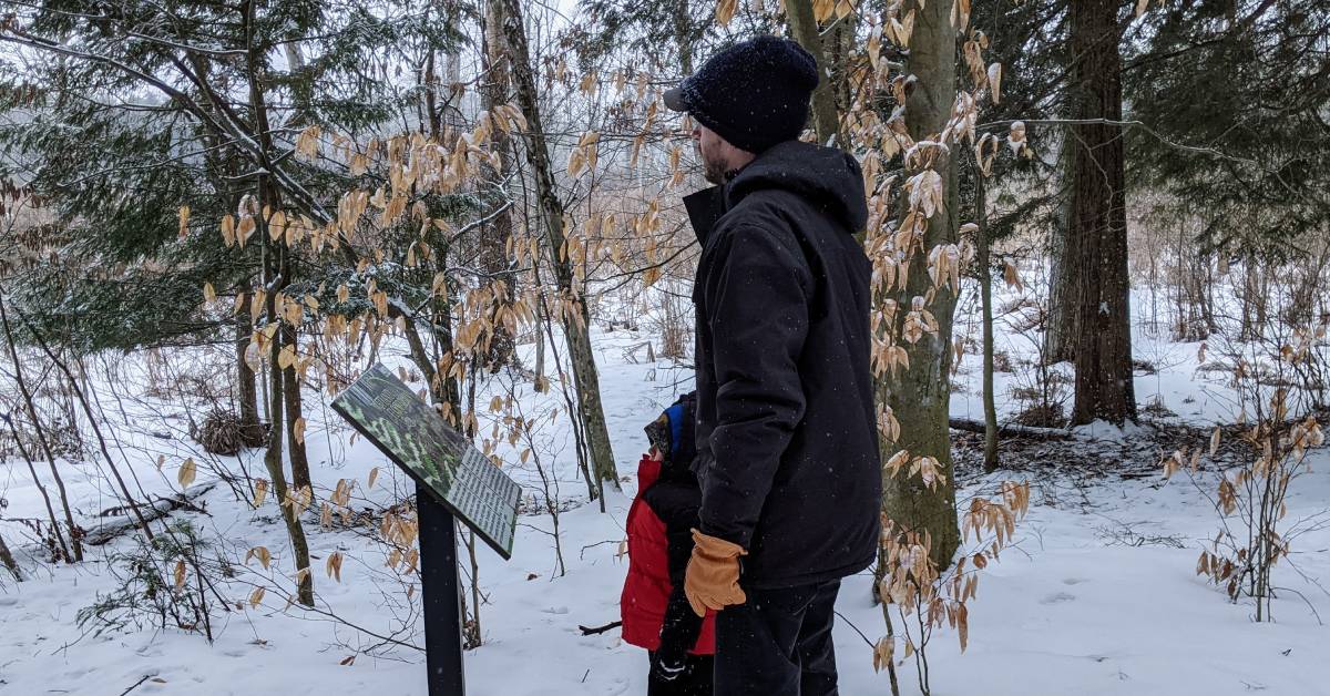 dad and son by signage on winter trail