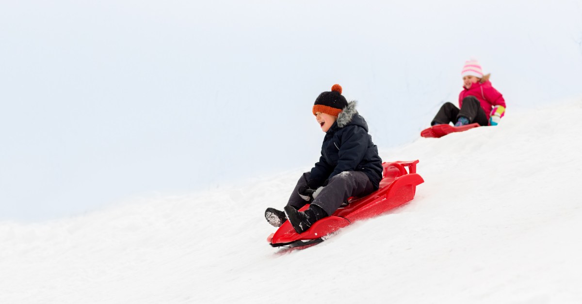 young boy and girl on red sleds in winter