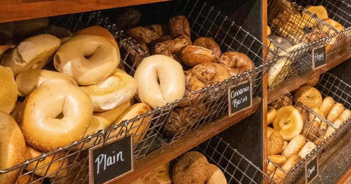 A bagel rack at Uncommon Grounds displaying freshly baked plain, poppyseed, and cinnamon raisin bagels.