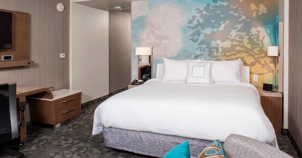 a hotel room with a bed and a wallpaper with tree design