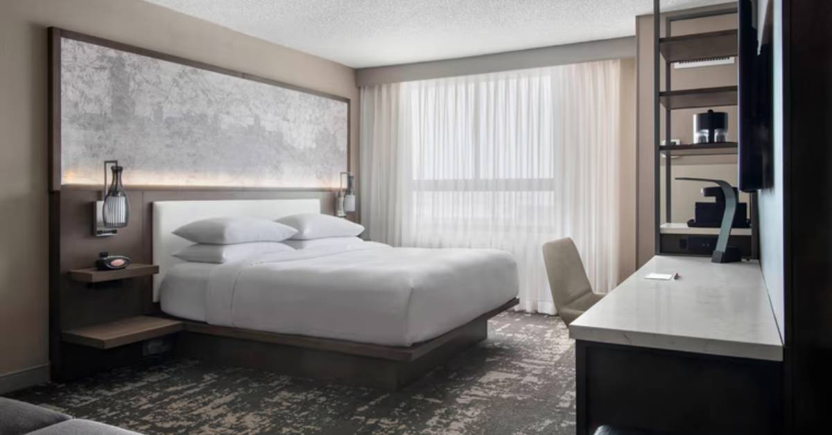 hotel room with a bed, desk, and white and grey decor