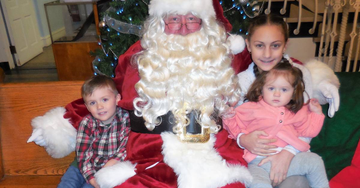 three kids sit with santa