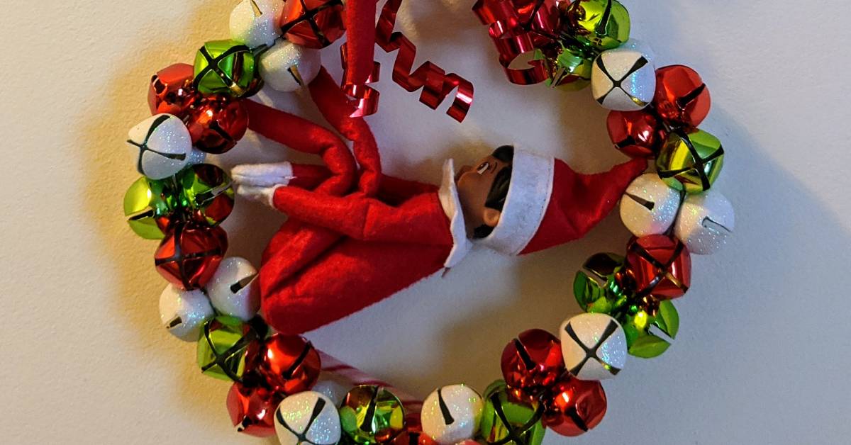 red, green, and white bell wreath with elf on the shelf