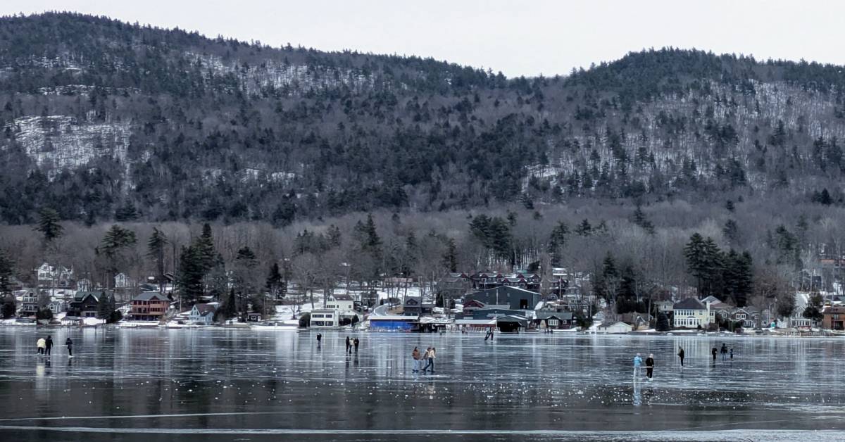 people walking and ice skating on lake george