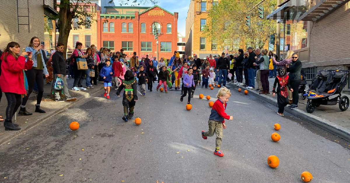 kids rolling pumpkins down a street