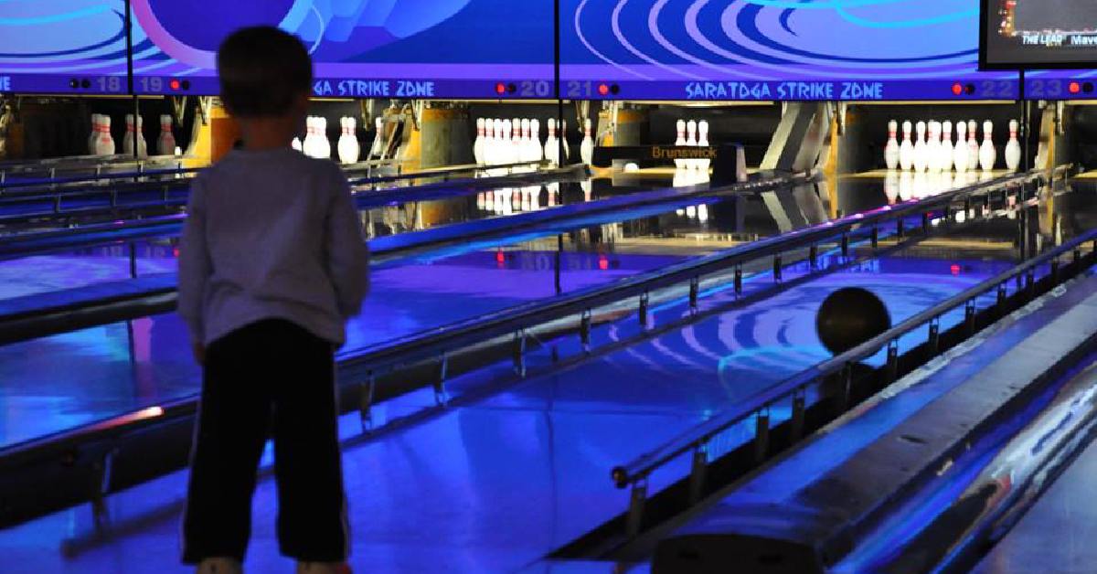 a boy watching a bowling ball roll