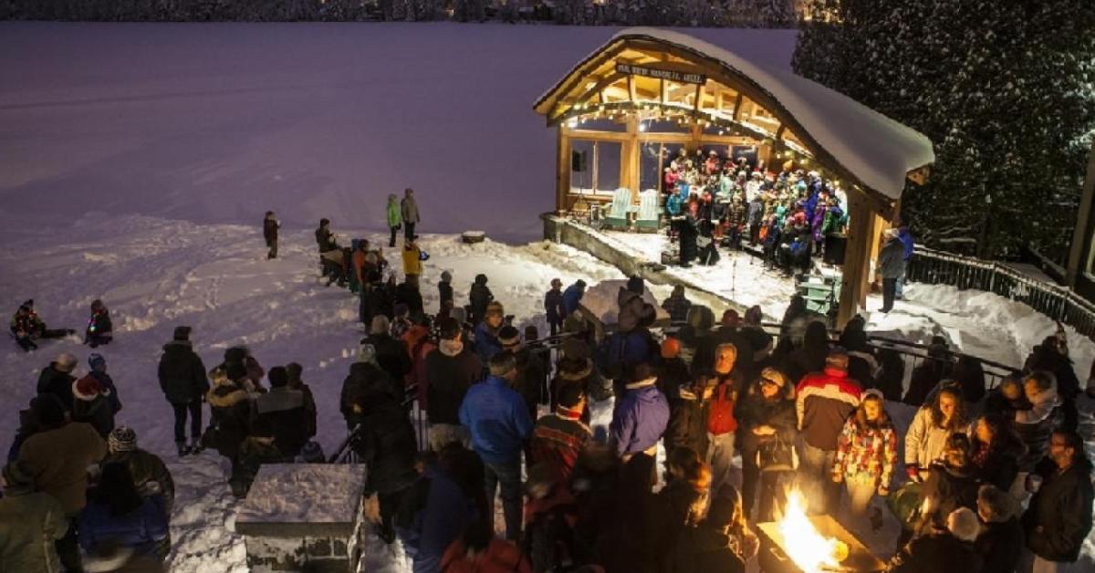 people standing near an outdoor amphitheater at night with a fire pit nearby and snow on the ground