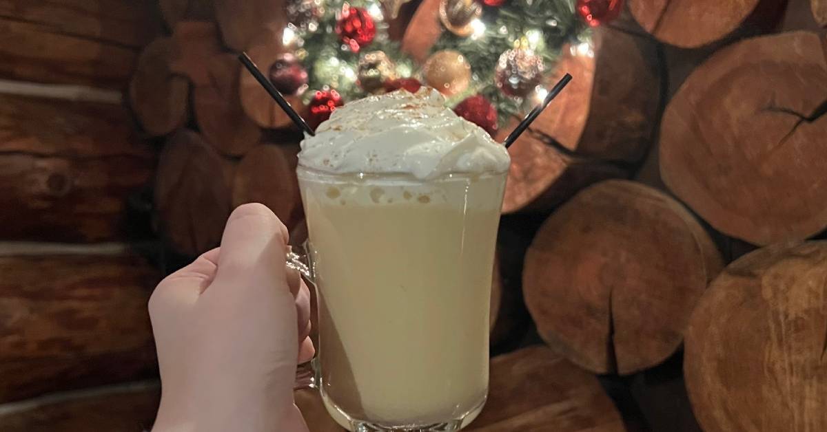 hand holding up winter cocktail against christmas decoration