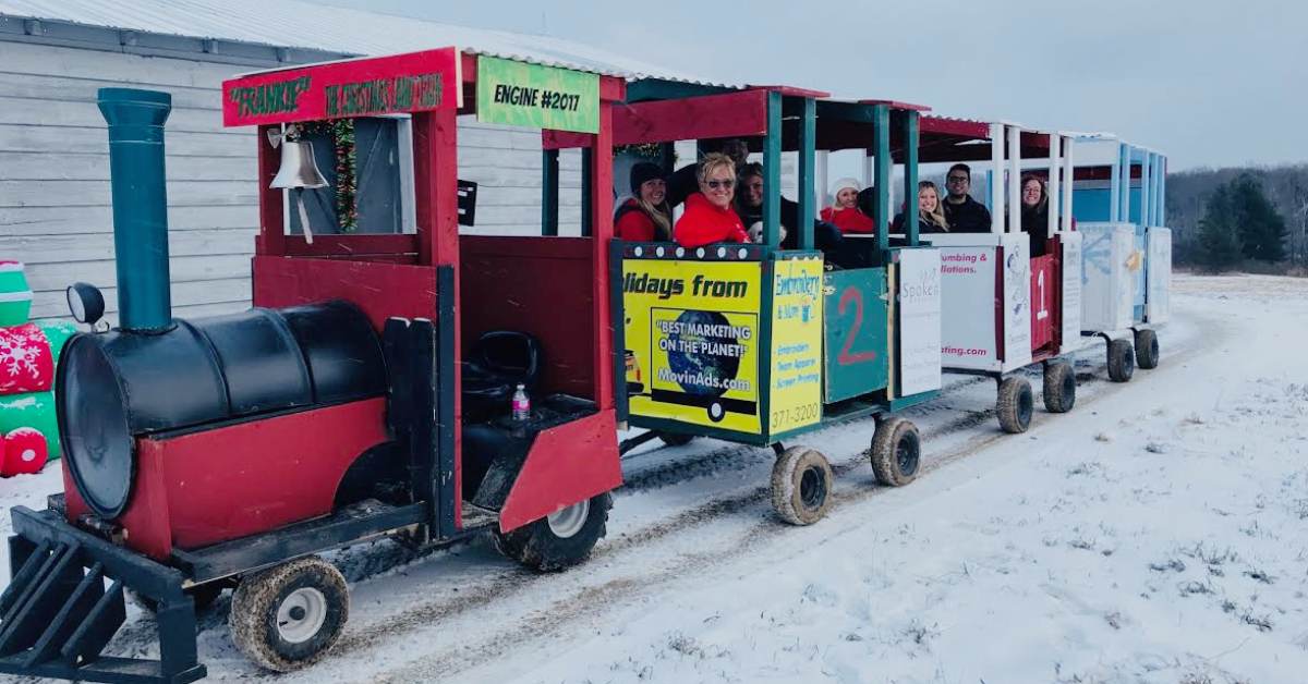 a small holiday themed train with people in it