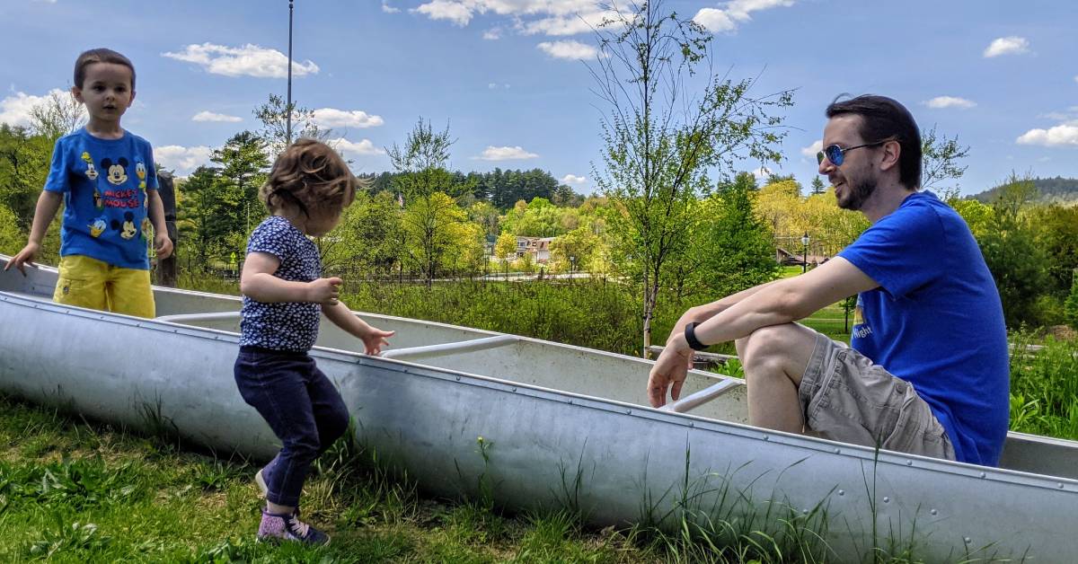 little kids and dad in canoe in park