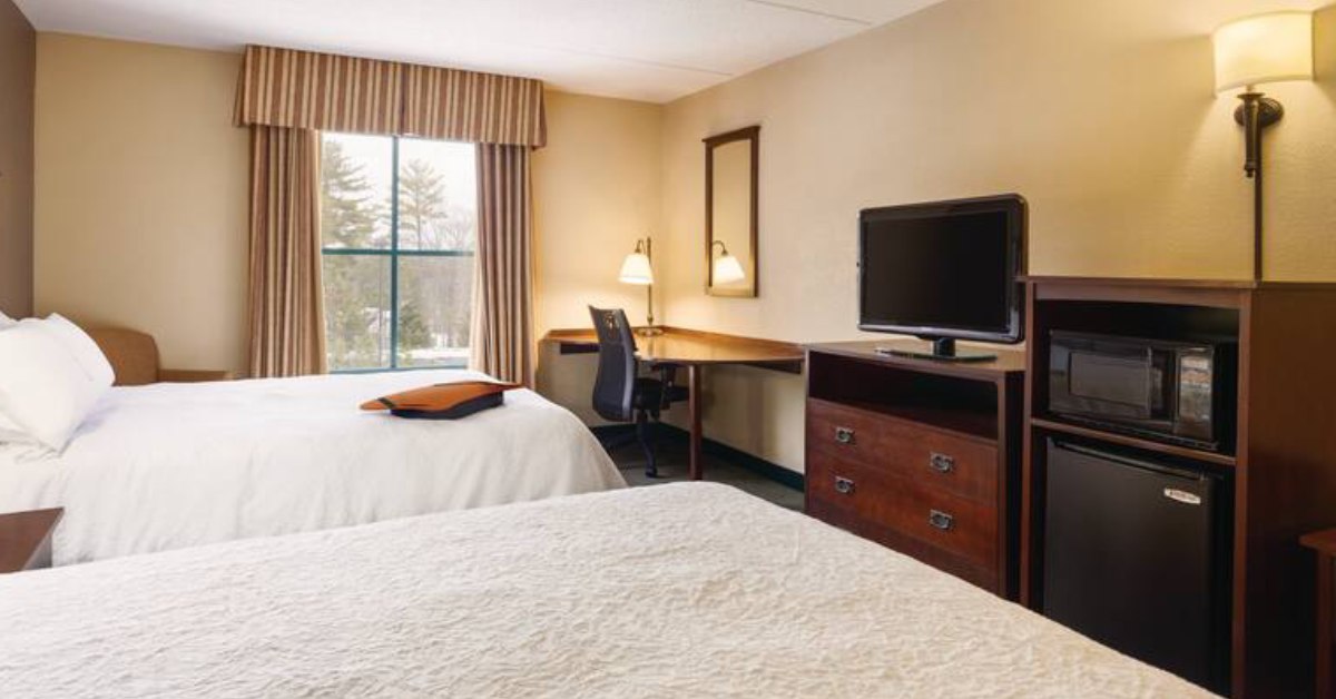 hotel room with two beds and TV and desk