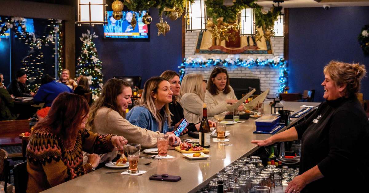 people seated at a bar and tables in a restaurant decorated for Christmas