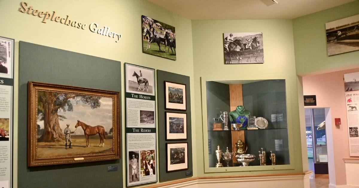 A display of trophies lines the wall in the Steeplechase Gallery at the National Museum of Racing, showcasing the rich history and prestige of racing.