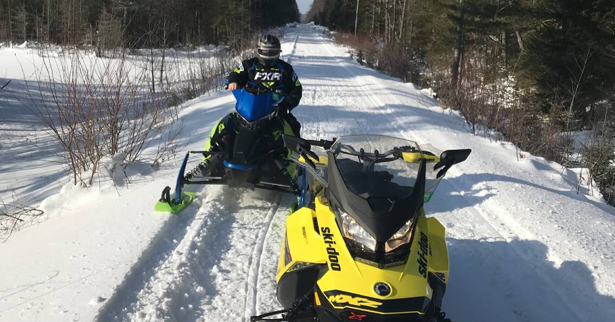 snowmobiler and snowmobile on trail