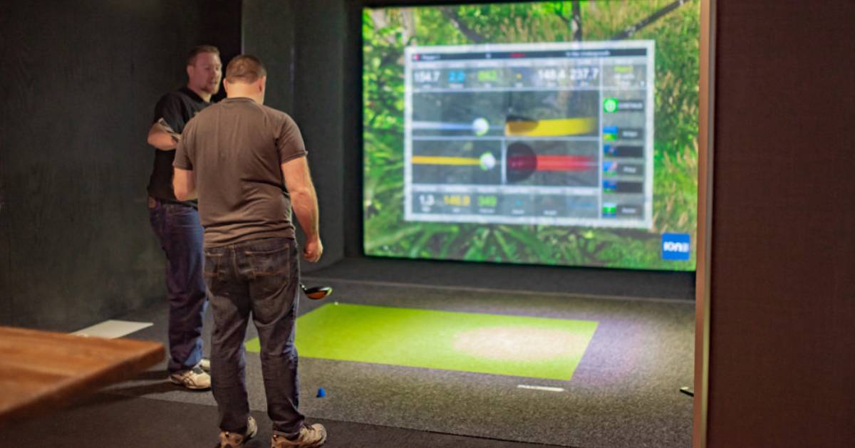 two men at a golf simulator screen