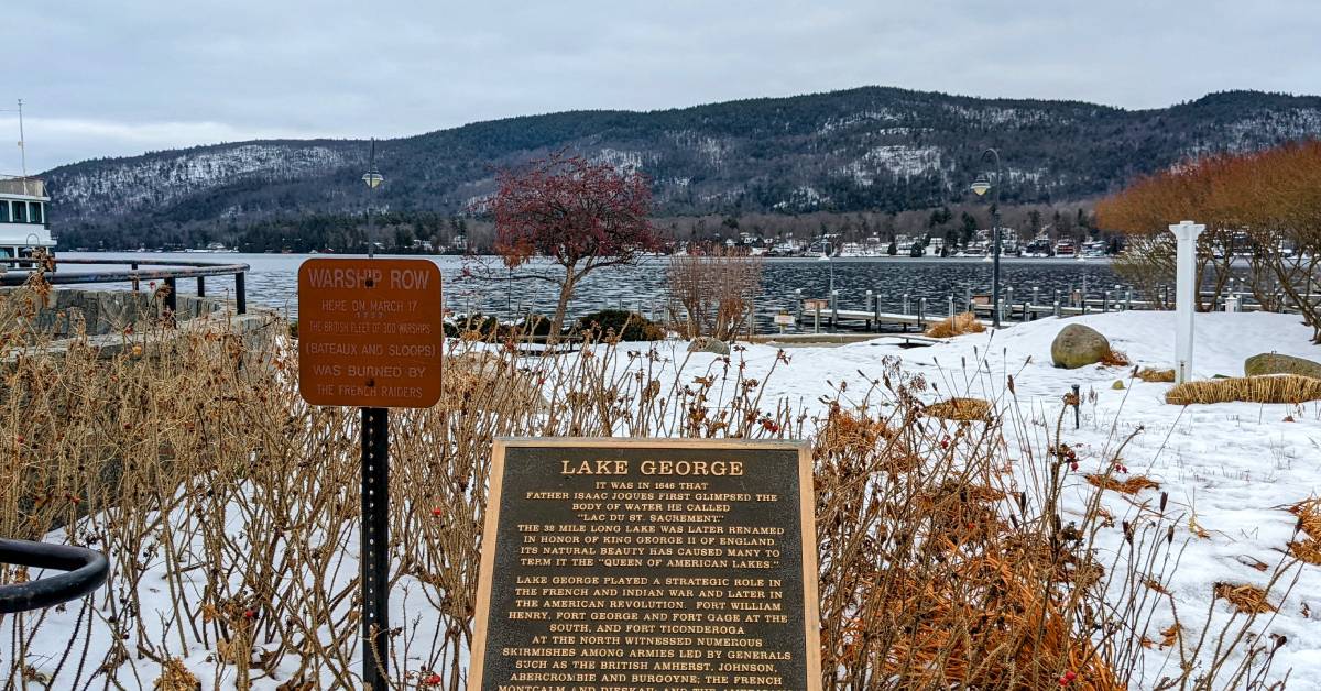 lake george sign in front of lake and mountains in winter