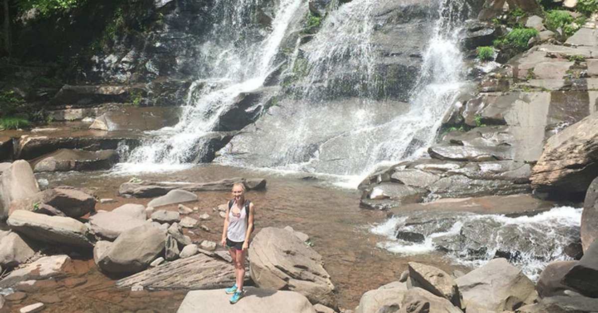 woman standing near bottom of waterfall