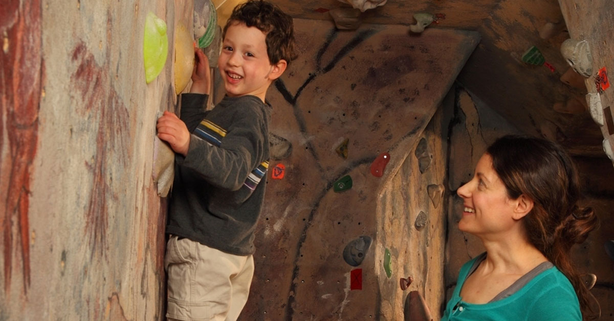 a kid rock climbing, mom watching