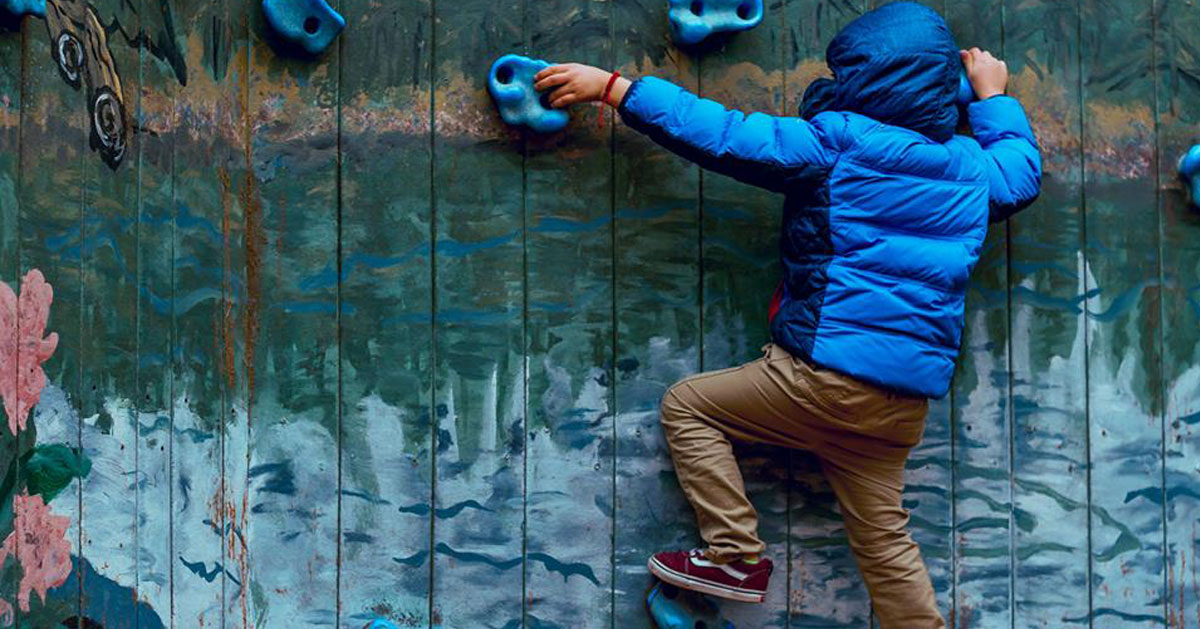 kid in blue jacket rock climbing