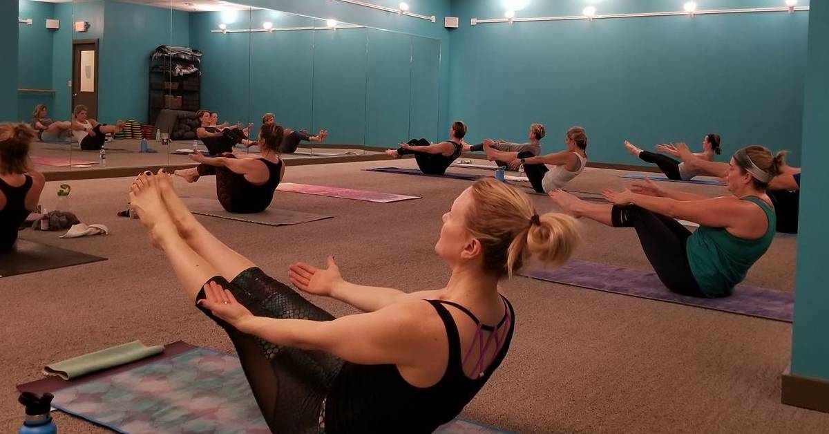 people doing boat pose in hot yoga class