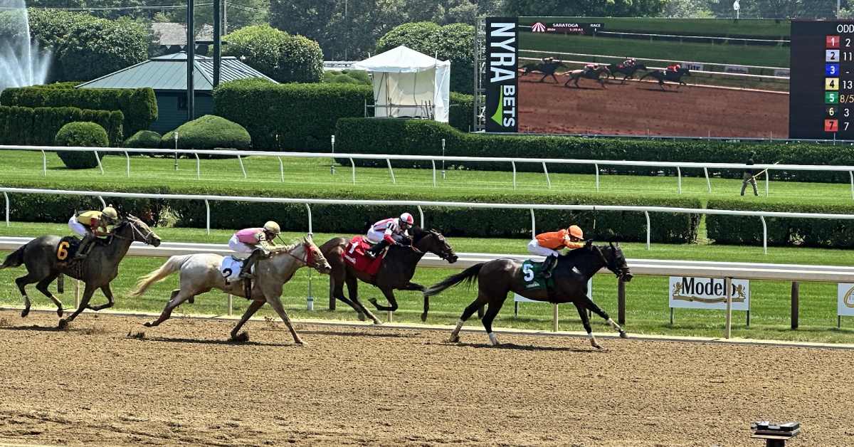 four race horses on a dirt track