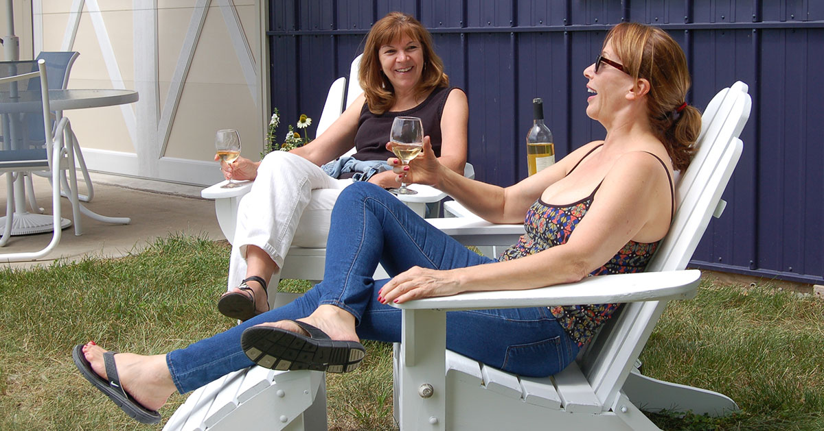 two women sitting with wine glasses