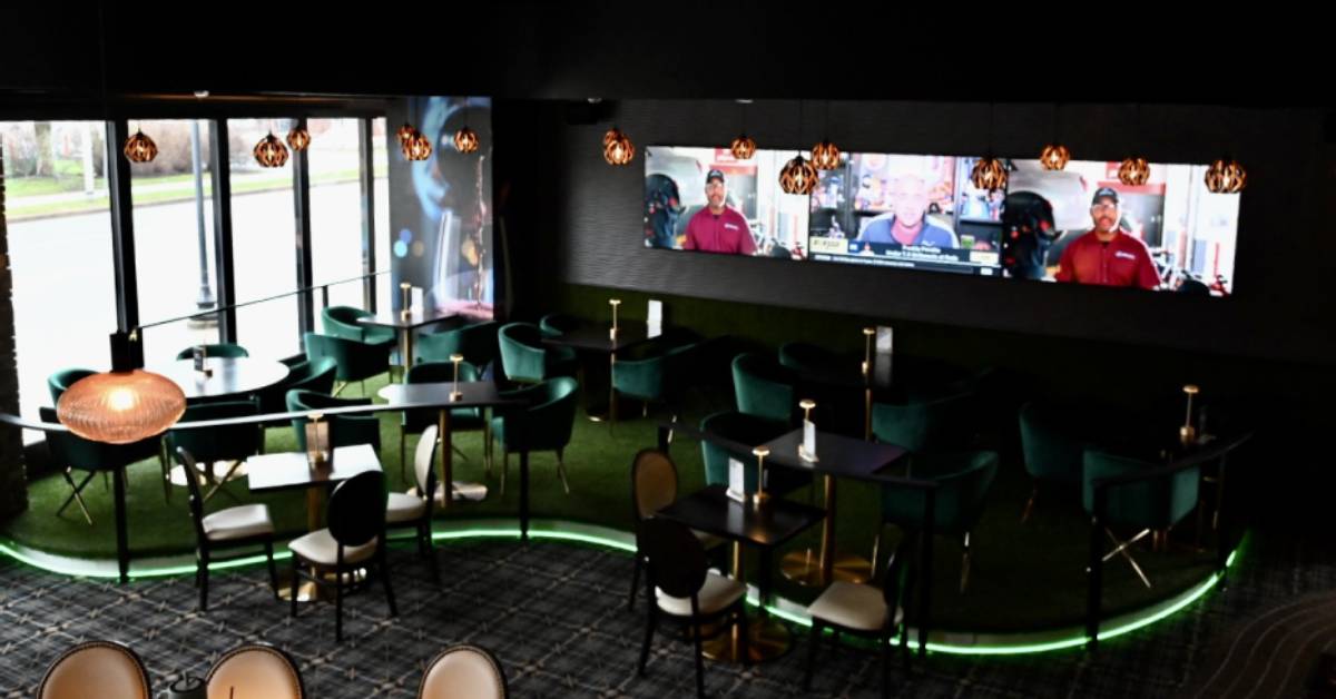 interior of a seating area with three large TV screens