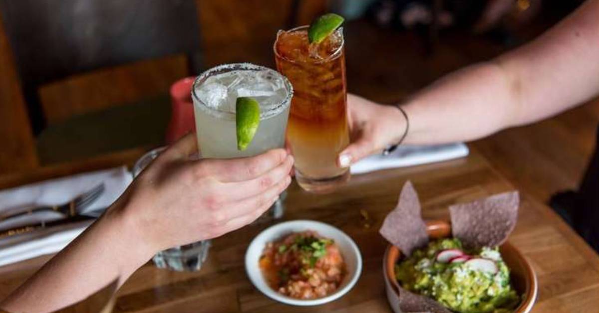 Two people raising their glasses and cheering their drinks