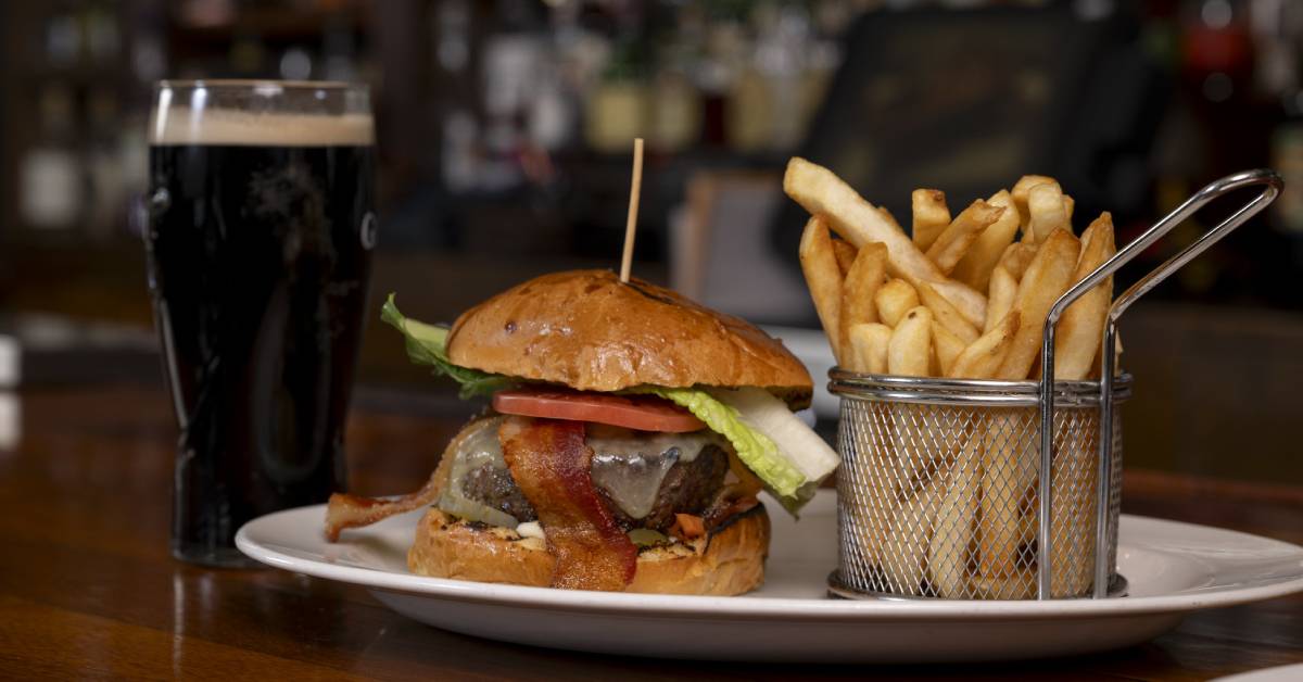 A glass of Guinness paired with a burger and fries