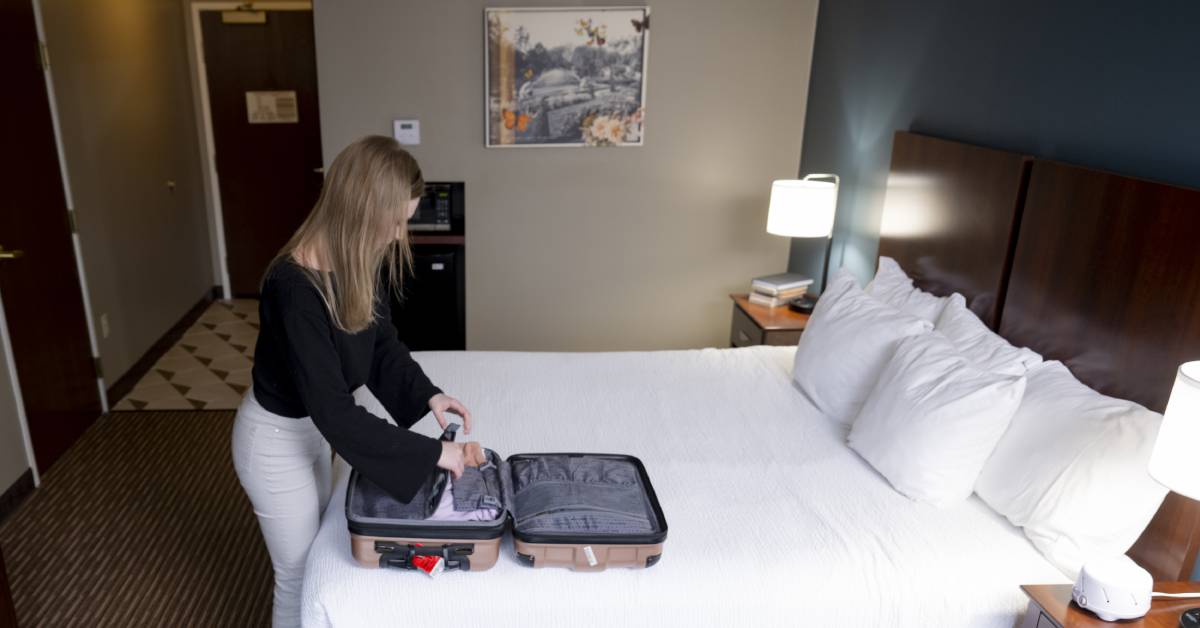 woman packs suitcase in hotel room