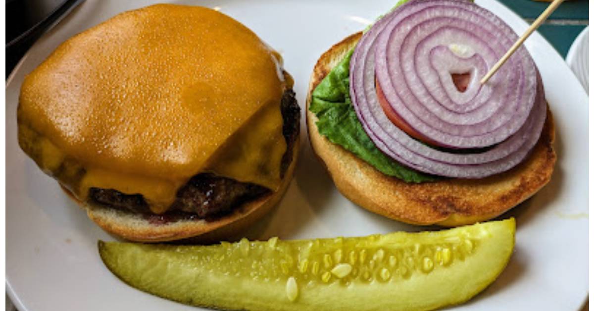Cheeseburger with lettuce, tomato, onion, and pickle on the side