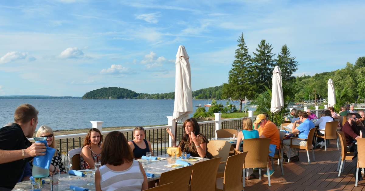 people dining outdoors on a patio by a lake