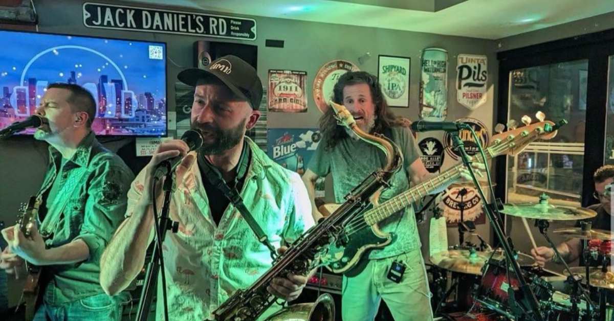 three people in a band performing on stage in a tavern