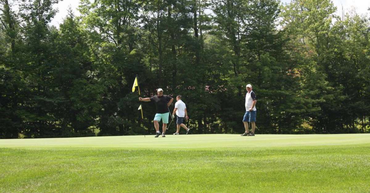 three men standing on the greens of a golf course
