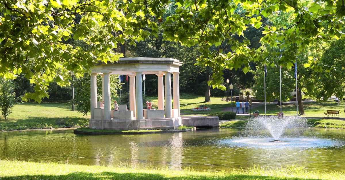 fountain in pond with stone gazebo nearby