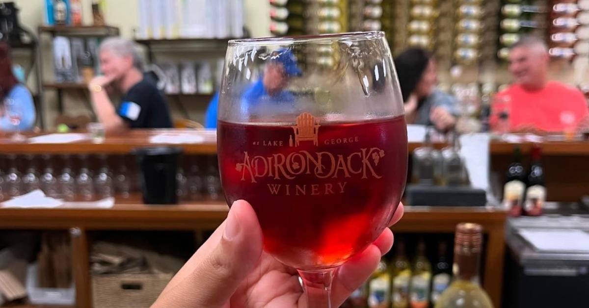 hand holding glass of adirondack winery wine at the winery
